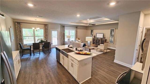 kitchen featuring stainless steel appliances, baseboards, dark wood-style floors, open floor plan, and a tray ceiling
