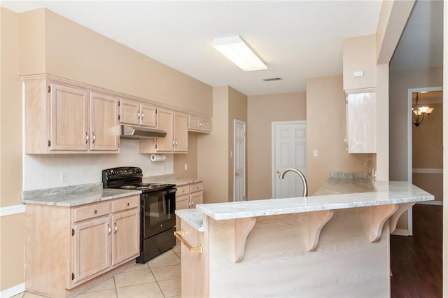 kitchen with a breakfast bar, black electric range oven, sink, light tile patterned flooring, and kitchen peninsula