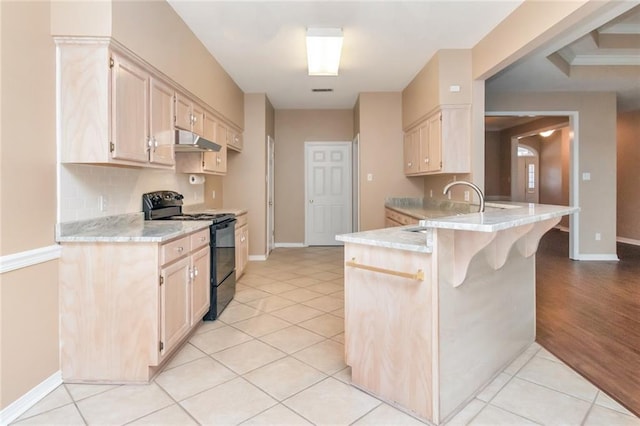 kitchen with a kitchen breakfast bar, black range with electric stovetop, sink, light hardwood / wood-style flooring, and kitchen peninsula