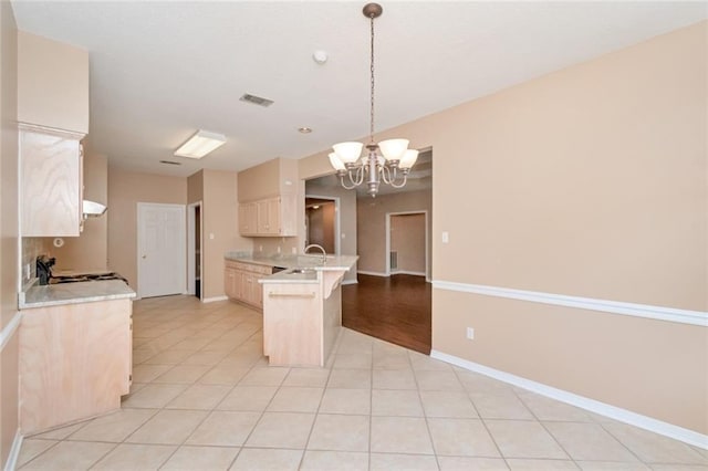 kitchen with stove, light tile patterned floors, decorative light fixtures, an inviting chandelier, and a breakfast bar area