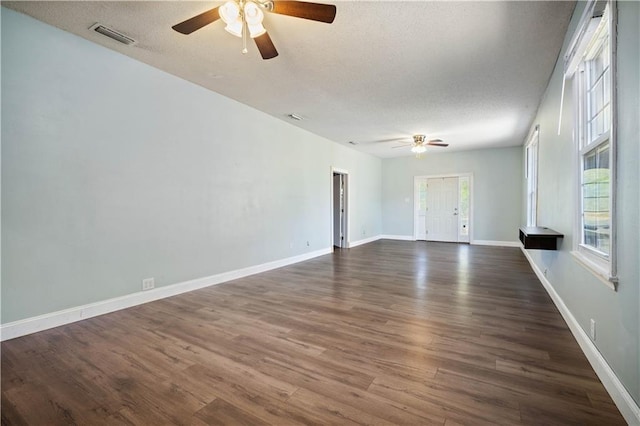 empty room with dark wood-type flooring, ceiling fan, and a textured ceiling