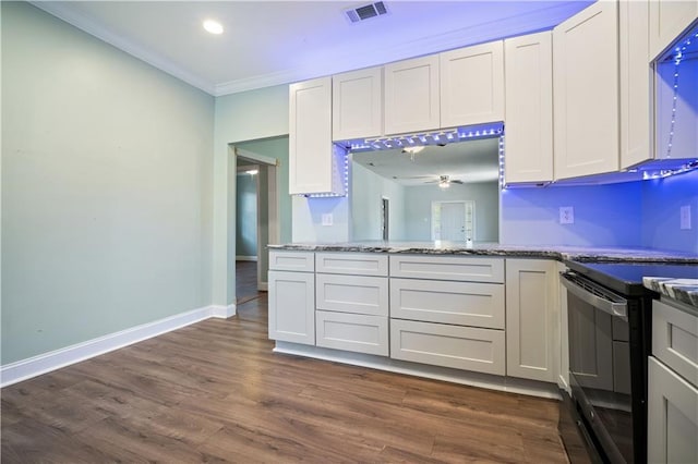 kitchen with dark wood-type flooring, black electric range oven, ornamental molding, light stone countertops, and white cabinets