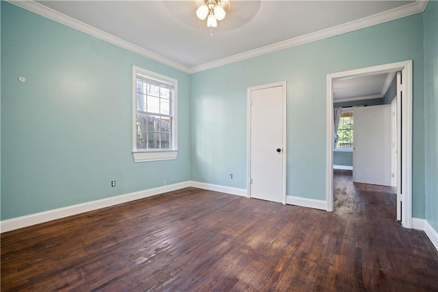 spare room featuring crown molding, dark wood-type flooring, a wealth of natural light, and ceiling fan