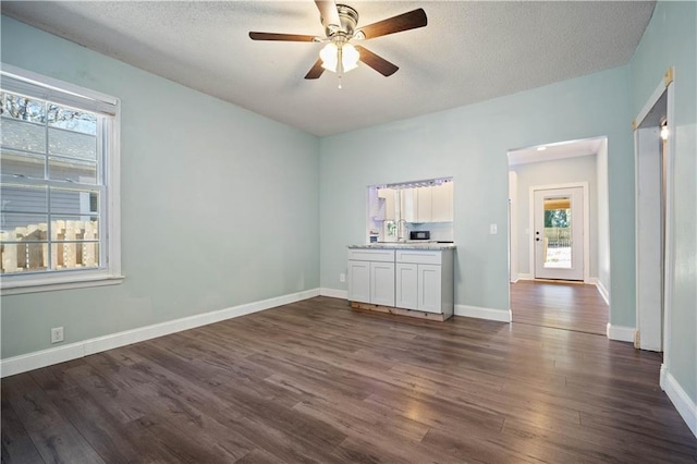 unfurnished living room featuring dark hardwood / wood-style floors, a textured ceiling, and ceiling fan