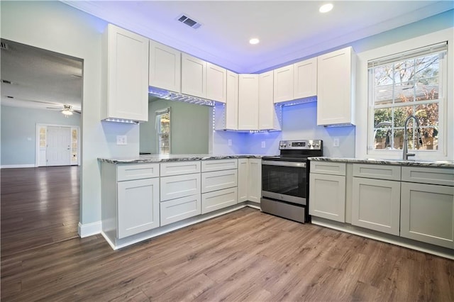 kitchen with electric range, white cabinets, and hardwood / wood-style flooring