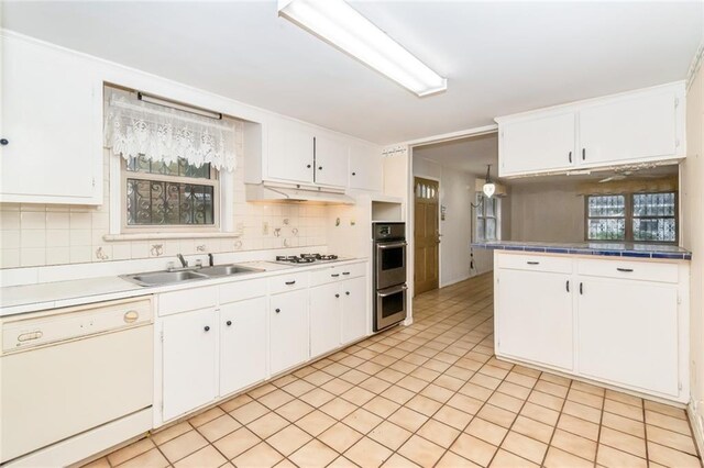 kitchen with white appliances, tasteful backsplash, a sink, and white cabinets