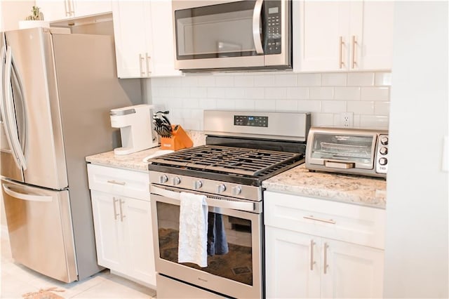 1660 Old Shell Rd, Mobile, AL 36604 - kitchen featuring appliances with stainless steel finishes, white cabinetry, decorative backsplash, light stone counters, and light tile patterned flooring