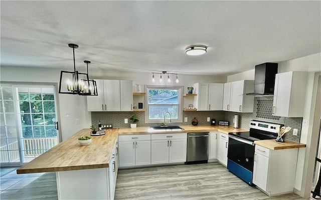 kitchen with wall chimney range hood, wood counters, white cabinets, appliances with stainless steel finishes, and sink