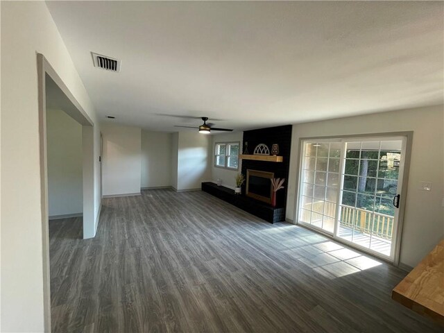 unfurnished living room featuring dark hardwood / wood-style flooring, plenty of natural light, ceiling fan, and a fireplace