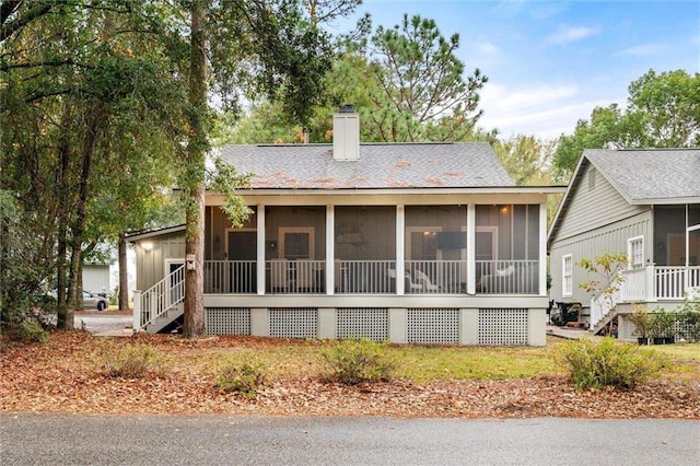 exterior space featuring stairway, a chimney, board and batten siding, and a sunroom