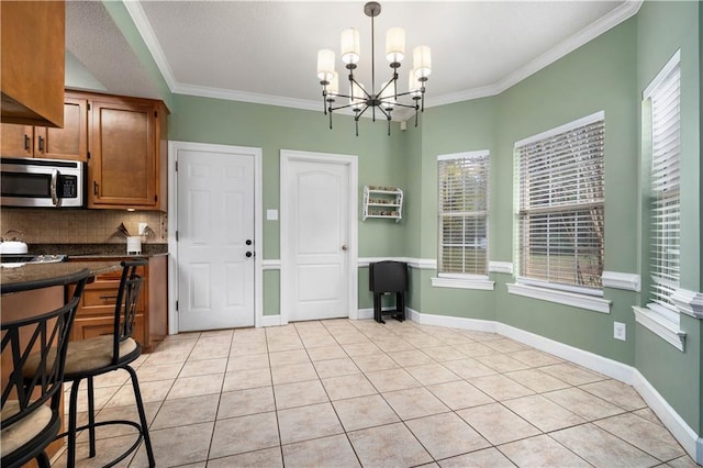 dining area with a notable chandelier, crown molding, baseboards, and light tile patterned floors