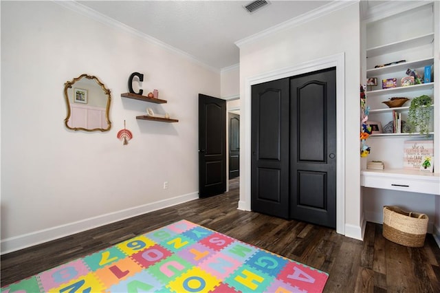 bedroom featuring dark wood finished floors, crown molding, a closet, visible vents, and baseboards