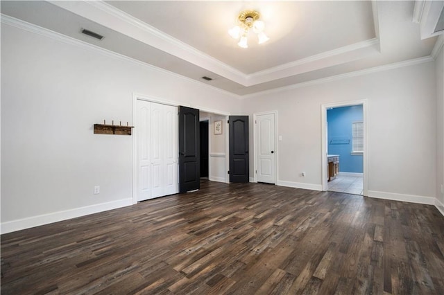 unfurnished bedroom with dark wood-style flooring, a raised ceiling, visible vents, and baseboards