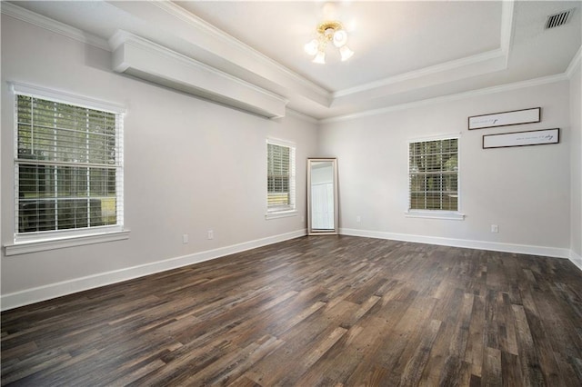 spare room featuring ornamental molding, dark wood-style flooring, a raised ceiling, and baseboards