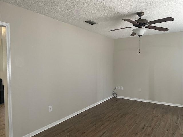 empty room featuring dark wood finished floors, visible vents, a textured ceiling, and baseboards