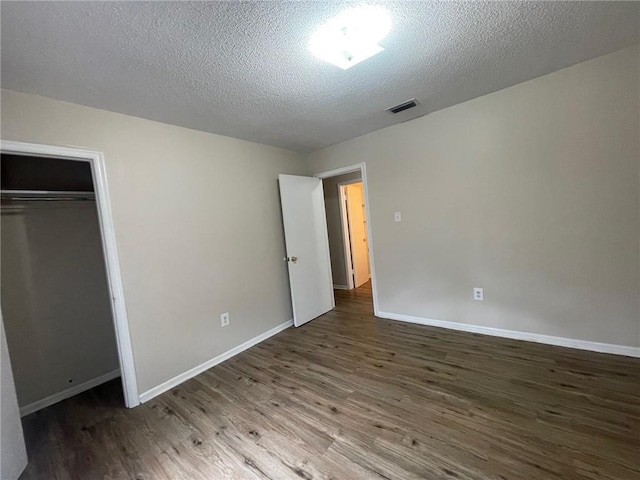 unfurnished bedroom featuring visible vents, baseboards, a textured ceiling, and wood finished floors