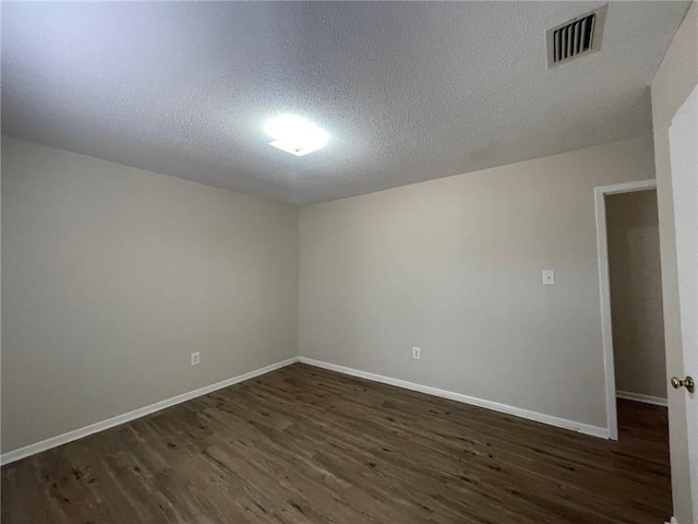 unfurnished room with visible vents, baseboards, a textured ceiling, and dark wood-style flooring