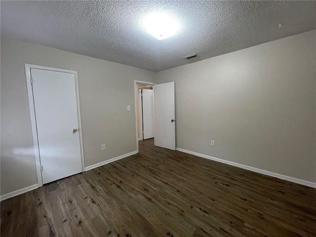 spare room featuring visible vents, a textured ceiling, baseboards, and wood finished floors