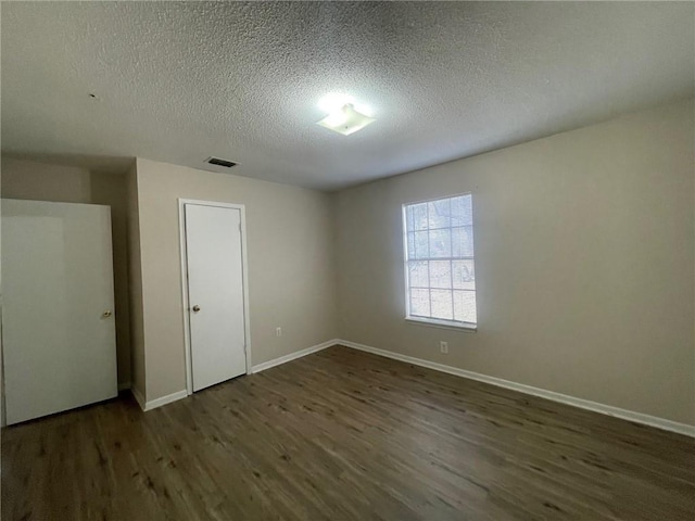 unfurnished room featuring visible vents, a textured ceiling, baseboards, and wood finished floors