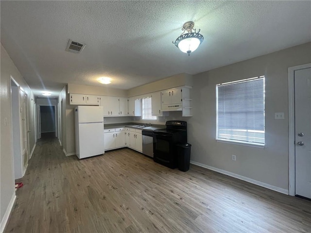 kitchen with visible vents, white cabinetry, freestanding refrigerator, black electric range, and dishwasher