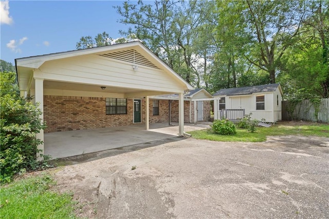 5902 Reams Dr S, Mobile, AL 36608 - rear view of house featuring brick siding, a carport, an outdoor structure, and asphalt driveway