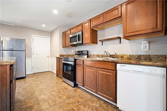 kitchen featuring sink, dark stone countertops, and stainless steel appliances