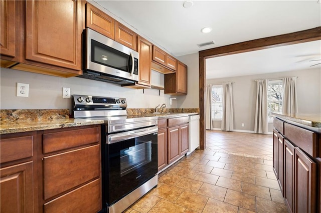 kitchen featuring appliances with stainless steel finishes, light stone counters, ceiling fan, sink, and light tile patterned floors