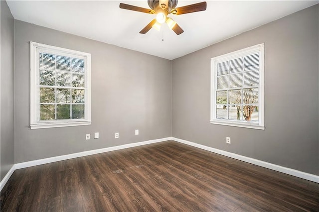 empty room featuring a wealth of natural light, ceiling fan, and dark hardwood / wood-style floors