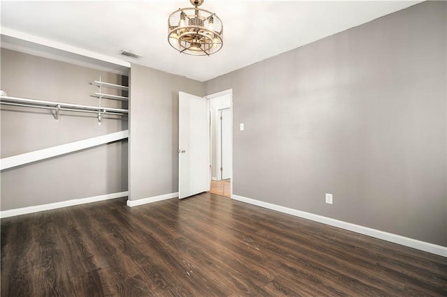 unfurnished bedroom featuring a closet, dark hardwood / wood-style flooring, and a chandelier