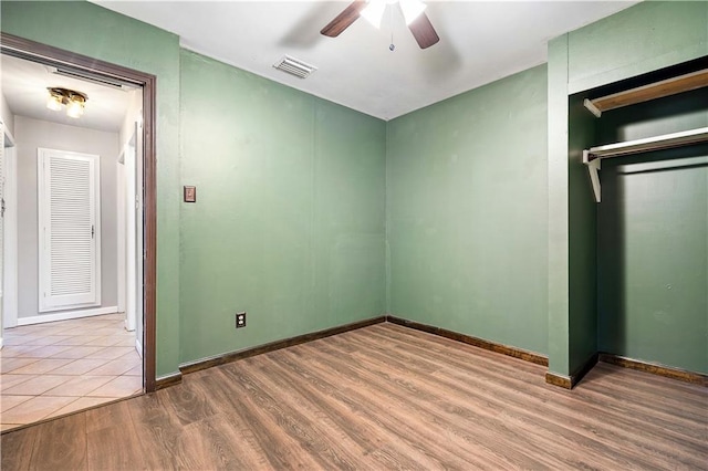 unfurnished bedroom featuring ceiling fan, wood-type flooring, and a closet