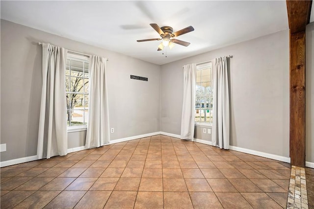 empty room featuring a wealth of natural light, light tile patterned floors, and ceiling fan