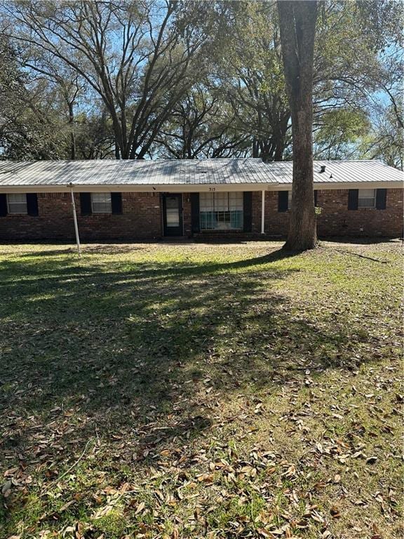 back of house with a yard, brick siding, and metal roof