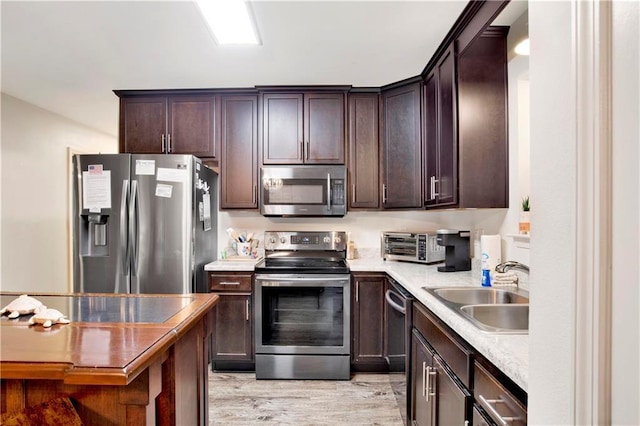 kitchen featuring sink, light wood-type flooring, appliances with stainless steel finishes, light stone counters, and dark brown cabinetry