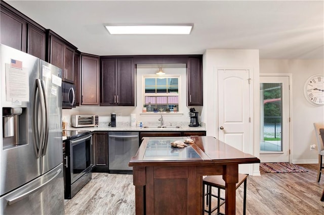 kitchen featuring decorative light fixtures, sink, light wood-type flooring, and stainless steel appliances