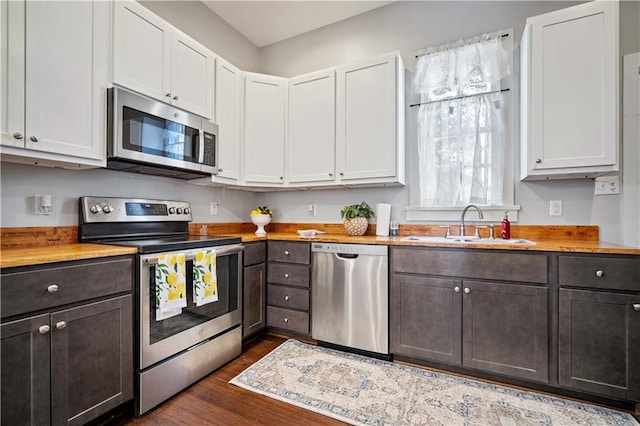 kitchen with dark wood-type flooring, appliances with stainless steel finishes, butcher block countertops, and white cabinets