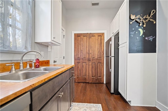 kitchen featuring white cabinetry, dark hardwood / wood-style flooring, sink, and stainless steel refrigerator