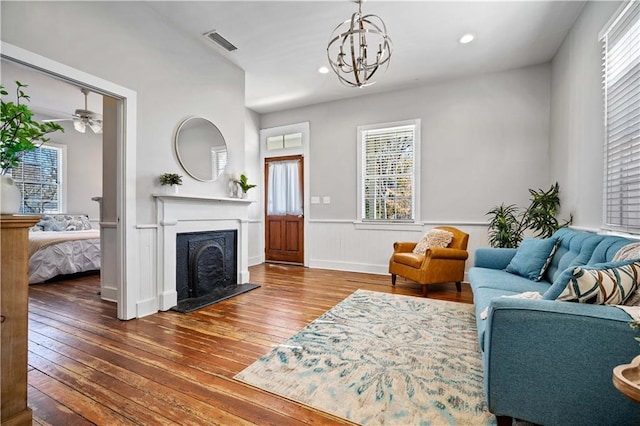 living room with hardwood / wood-style flooring, ceiling fan with notable chandelier, and a healthy amount of sunlight