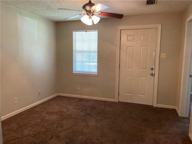 spare room featuring a textured ceiling, ceiling fan, and dark colored carpet