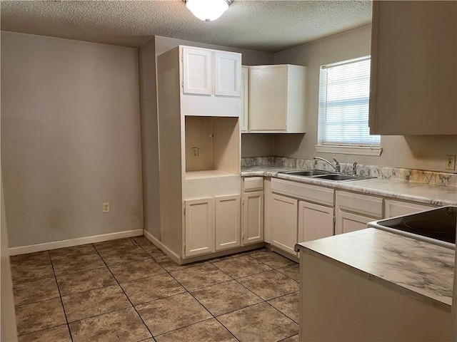 kitchen with white cabinets, a textured ceiling, sink, and tile flooring