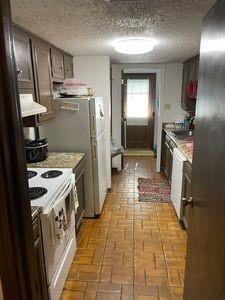 kitchen with a textured ceiling, white electric stove, and dark brown cabinetry