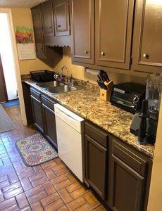 kitchen with light stone countertops, dishwasher, sink, and dark brown cabinetry