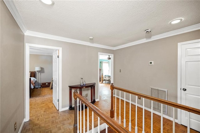 hall with light parquet floors, a textured ceiling, and ornamental molding