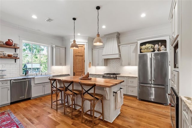 kitchen featuring a kitchen breakfast bar, gray cabinetry, a kitchen island, stainless steel appliances, and light hardwood / wood-style flooring