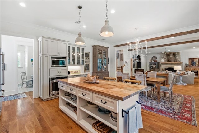 kitchen featuring light hardwood / wood-style floors, white cabinetry, a fireplace, butcher block counters, and stainless steel appliances