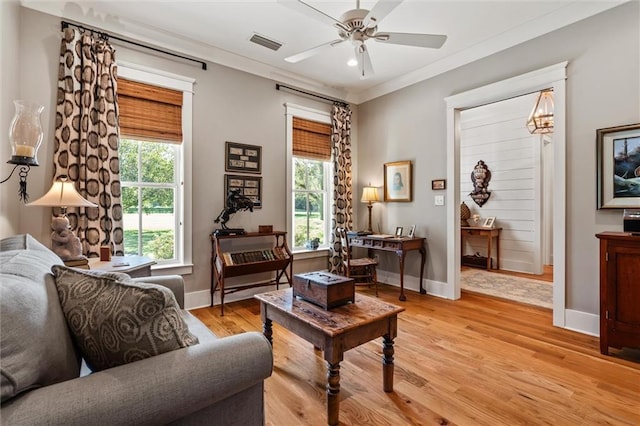 living room featuring light wood-type flooring, ceiling fan with notable chandelier, and plenty of natural light