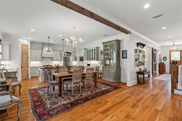 dining room featuring ornamental molding, light wood-type flooring, and an inviting chandelier