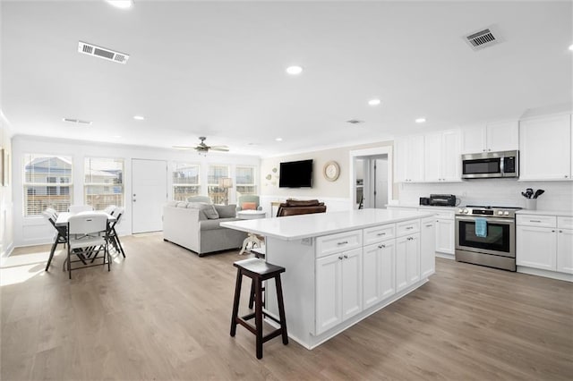 109 Quebec Ct, Dauphin Island, AL 36528 - kitchen featuring stainless steel appliances, a kitchen island, light countertops, white cabinets, and ornamental molding
