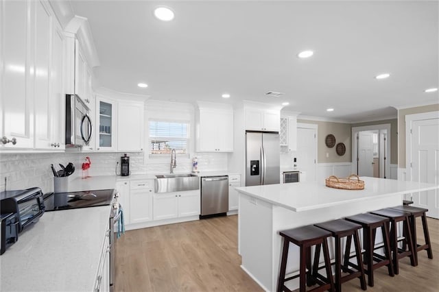 109 Quebec Ct, Dauphin Island, AL 36528 - kitchen featuring stainless steel appliances, a sink, a kitchen bar, ornamental molding, and white cabinets