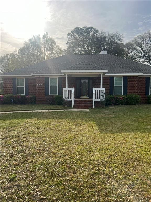 ranch-style house with brick siding, covered porch, a front yard, and a chimney