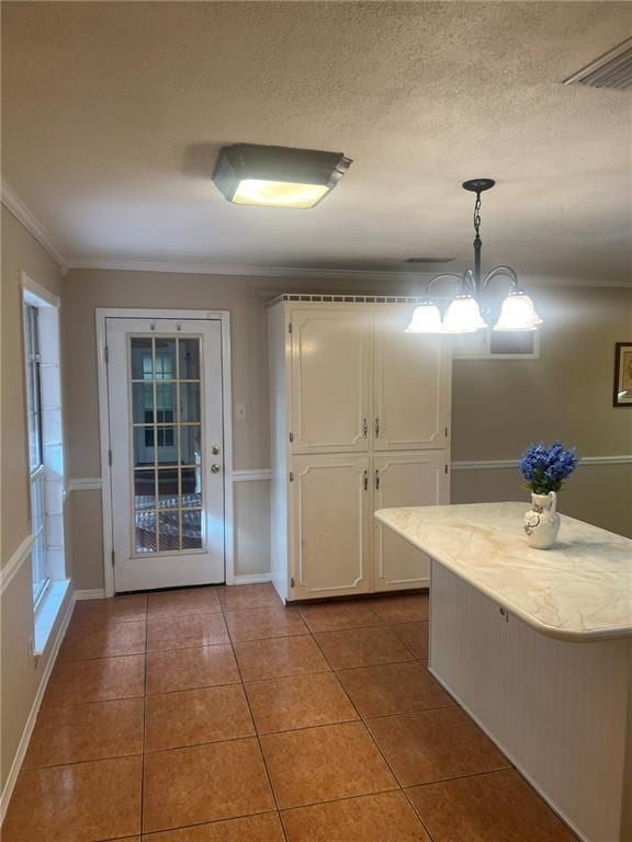 kitchen featuring white cabinetry, tile patterned floors, light countertops, pendant lighting, and crown molding